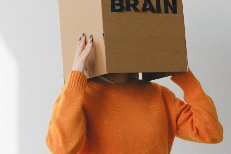 Discovering Purpose. - Crop person putting Idea title in cardboard box with Brain inscription on head of female on light background